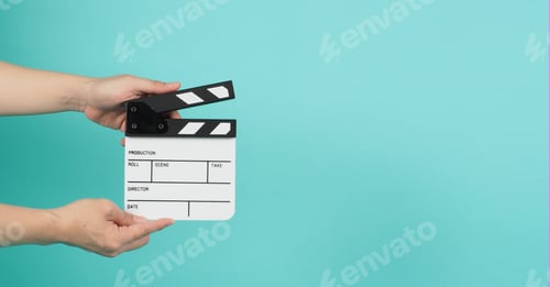 Preview: Hand is holding clapper board on green mint or Tiffany Blue background.