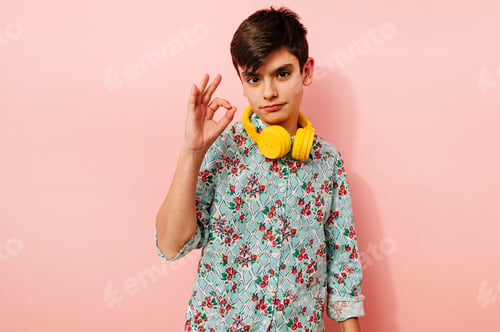 Preview: Young guy with yellow headphones in studio on pink background.