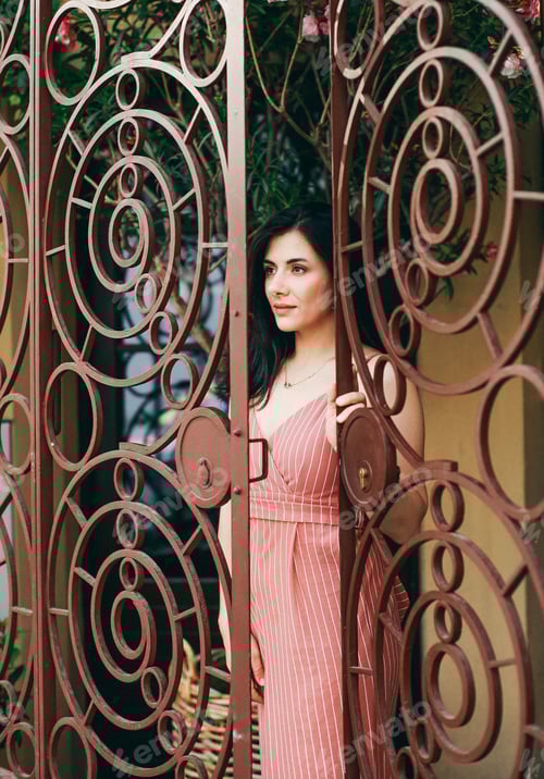 Preview: Woman Posing by Ornate Gate with Floral Background