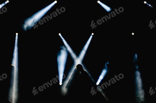 Preview: Silhouette of some workers illuminated by the spotlights of a stage
