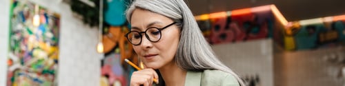 Preview: Mature grey thinking woman working with planner in cafe indoors