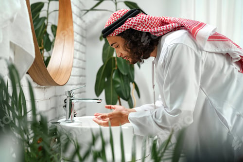 Preview: Young Arab man getting ready and looking at the mirror in the bathroom