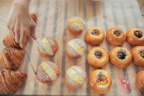Preview: Female hand taking cake from display showcase in bakery shop