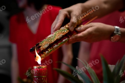 Preview: Hand holding joss sticks and candle as prayer and offering to the Gods