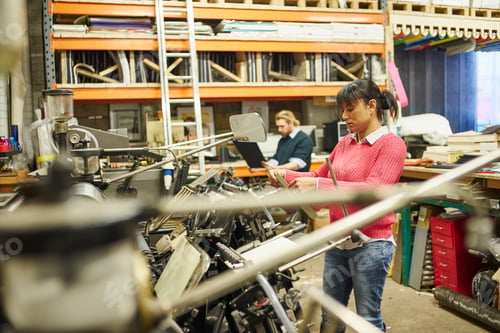 Preview: Male and female printers using old printing machine in traditional print workshop
