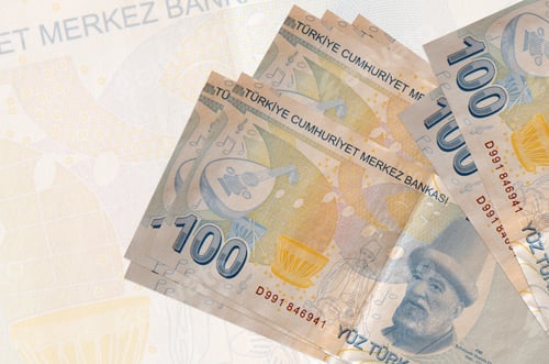 Preview: 100 Turkish liras bills lies in stack on background of big semi-transparent banknote. Abstract pres
