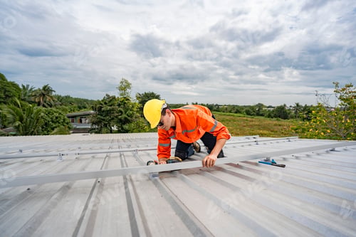 Preview: Technician in safety uniform and helmet kneeling on a rooftop