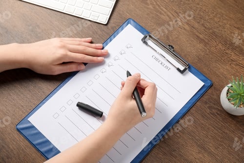 Preview: Woman filling Checklist at wooden table, above view