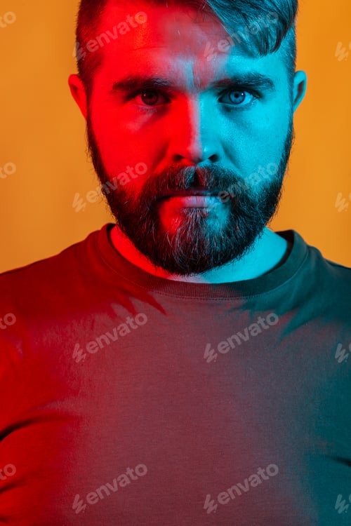 Preview: Neon light studio portrait of attractive male model with mustaches and beard wears t-shirt, close-up