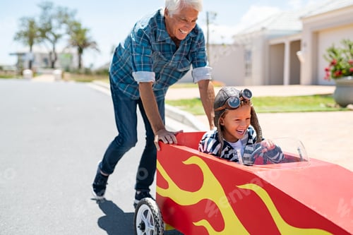 Preview: Grandfather pushing his little boy on toy car