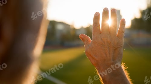 Preview: Old man grandfather pensioner looking sunrise sun through palm hand morning close up unrecognizable