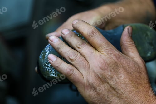 Preview: Closeup shot of the hand of a shoe maker preparing his working tools with blur background