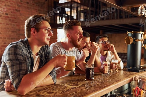 Preview: With beer in hands. People in casual clothes sitting in the pub