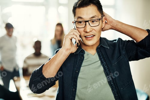 Preview: Asian businessman standing in an office talking on a cellphone