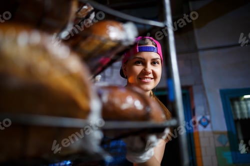 Preview: A young girl works in a bakery. She puts bread on a shelf. Woman baker at workplace