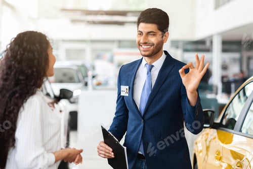 Preview: Attractive car showroom manager showing okay gesture
