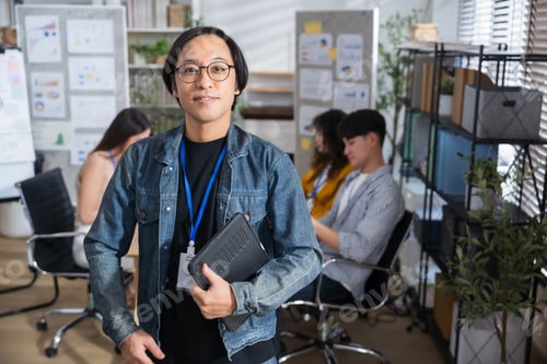 Preview: Portrait creative Asian businessman holding digital tablet laptop at at creative office workplace.