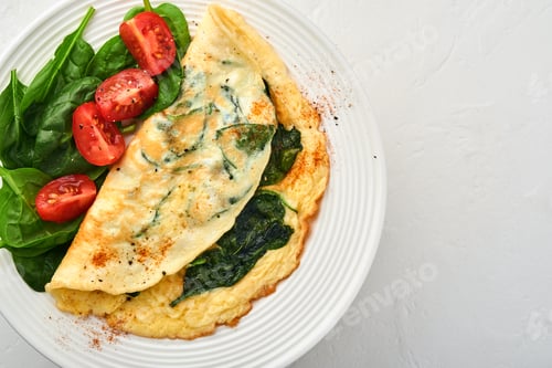 Preview: Omelet or omelette with spinach, cherry tomato and pepper seasoning on a white plate, on white backg