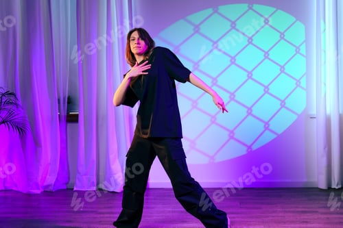 Preview: Female dancer performs expressive routine under colorful lights in studio setting