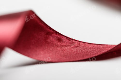 Preview: close up of shiny silk curved burgundy ribbon on grey background