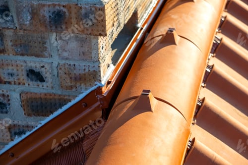 Preview: Closeup of yellow ceramic roofing ridge tiles on top of residential building roof