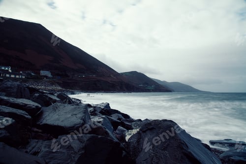 Preview: Scenic view of rocky beach in the coast of Ireland against mountain