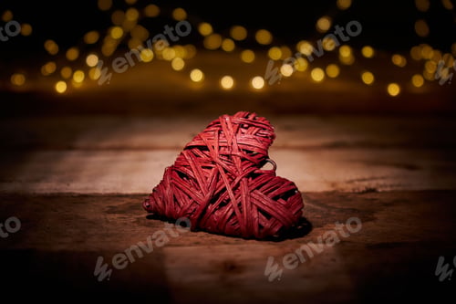 Preview: Woven heart on a wooden floor with bokeh in the background