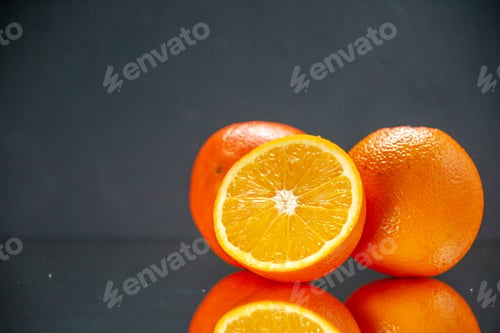 Preview: Top view of whole cut fresh oranges standing side by side on the left side on light on black
