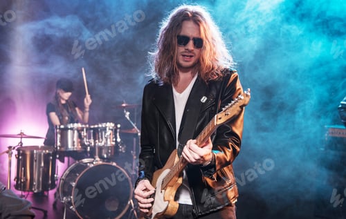 Preview: Electric guitar player with rock and roll band performing hard rock music on stage