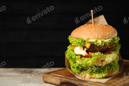 Preview: Burger with delicious patty on wooden table against dark background, space for text
