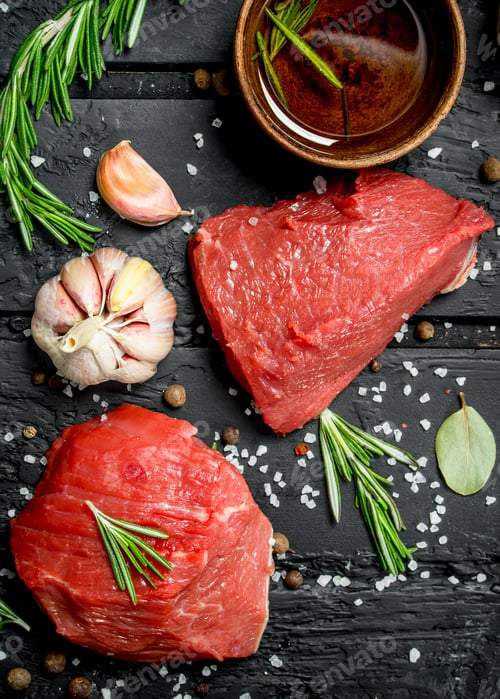 Preview: Raw meat. Sliced pieces of beef with spices and herbs on a wooden Board.