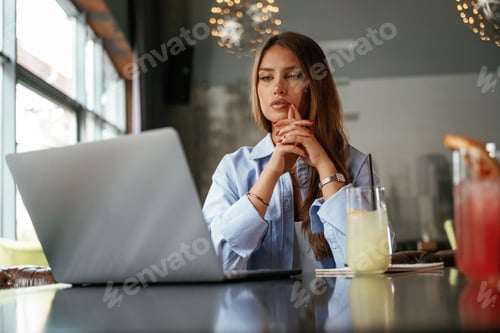 Preview: Cocktail is on the table. Beautiful woman with laptop is in the bar