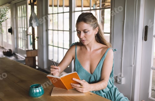 Preview: Young Woman Writing in a Notebook at Home