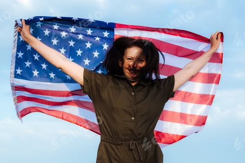 Preview: Beautiful happy woman with american flag celebrating and jumping, happy birthday America!