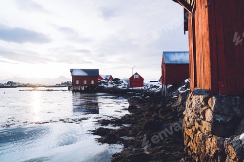 Preview: Wooden cabins on seashore surrounded by snowy mountains