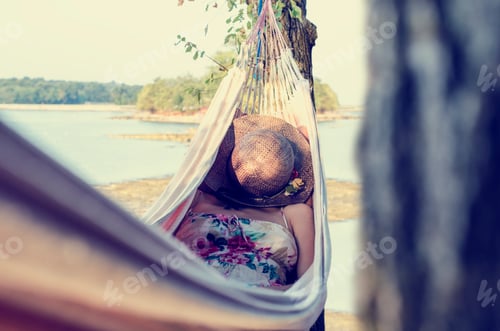 Preview: Woman relaxing in a hammock, next to a lake