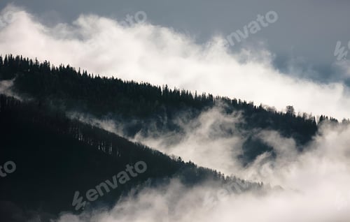 Preview: Dramatic cloudy sky above a mountain range covered in forests