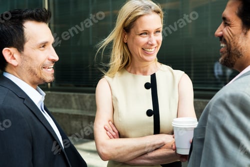 Preview: Businesswoman and two businessman standing outdoors, chatting and smiling.