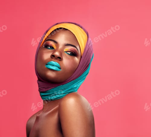 Preview: Studio shot of a beautiful young woman wearing a head wrap and make up against a pink background