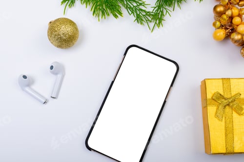 Preview: Composition of smartphone with copy space, wireless earphones and christmas decorations on white