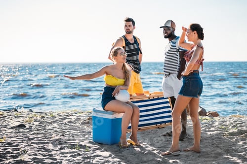 Preview: happy young multiethnic friends with beach items spending time on sandy sea coast