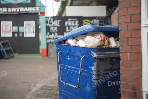 Preview: Selective focus shot of an old blue waste container full of trash