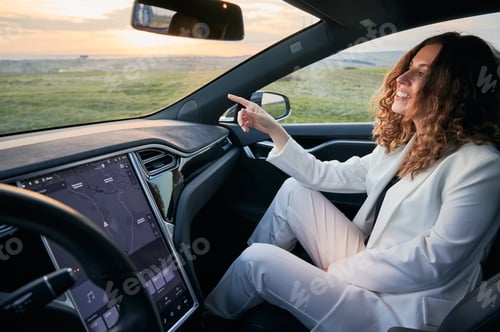 Preview: Female passenger in car pointing to road ahead.