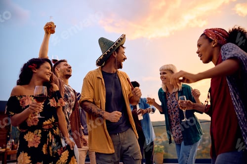Preview: Cheerful friends dancing and having fun while having a party on a patio.