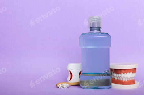 Preview: Mouthwash and other oral hygiene products on colored table top view with copy space