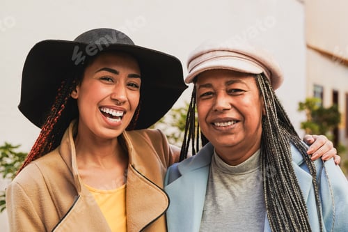 Preview: Happy african mother and daughter smiling in front of camera during winter time