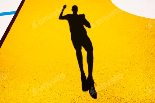 Preview: Shadow and silhouette of a man jumping on a yellow painted floor.