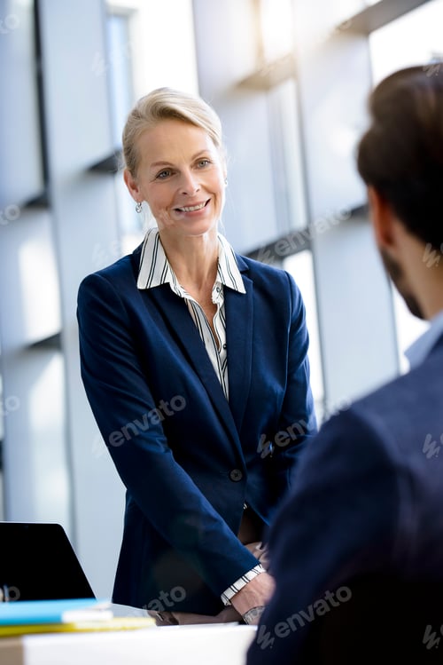Preview: Over shoulder view of businesswoman and man having discussion at office desk