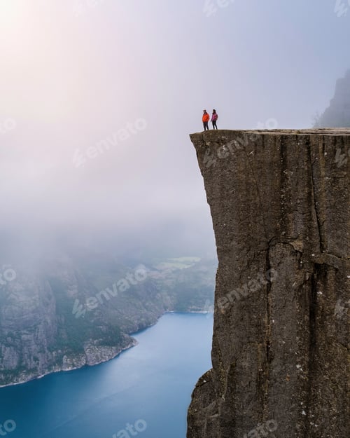 Preview: A breathtaking view from the top of the Preikestolen cliff in Norway, with two figures standing at