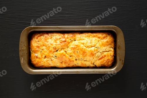 Preview: Homemade Cheesy Bread Loaf on a black background, top view. Flat lay, overhead, from above.